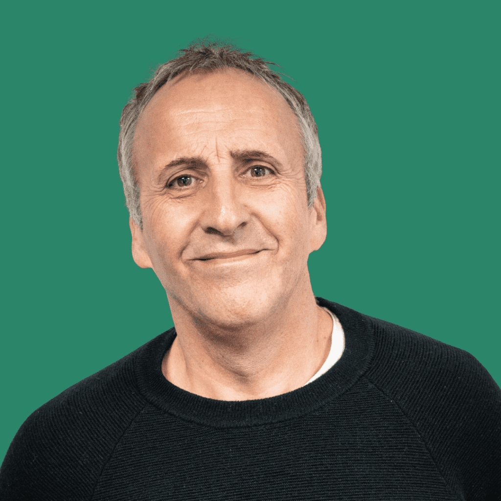 Man with black jumper and grey hair smiling